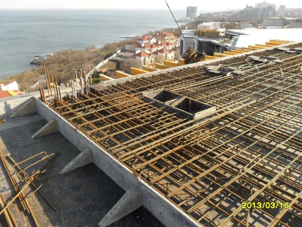 Shared office and hospitality estate: reinforcement across an upper slab, with the coast beyond. Site report, 2013.