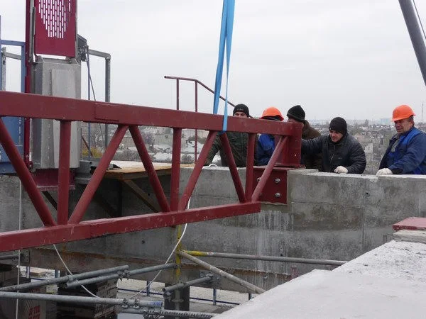 Historic-centre commercial building: lifting equipment and workers at roof level. Site-report photograph.