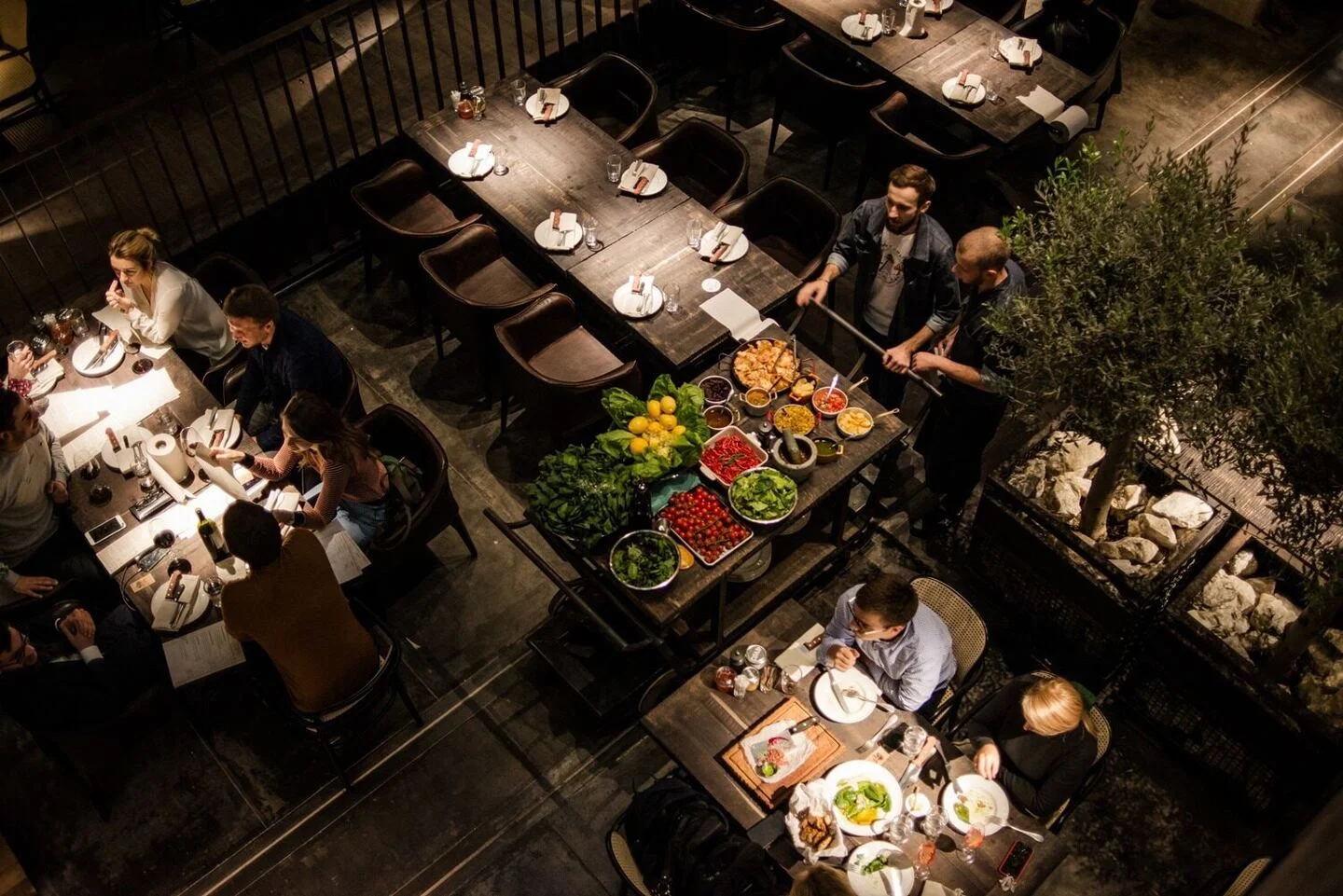 Steakhouse Kyiv: the dining room in use, with tables arranged around planted dividers. Project photograph; interior design by the appointed team.