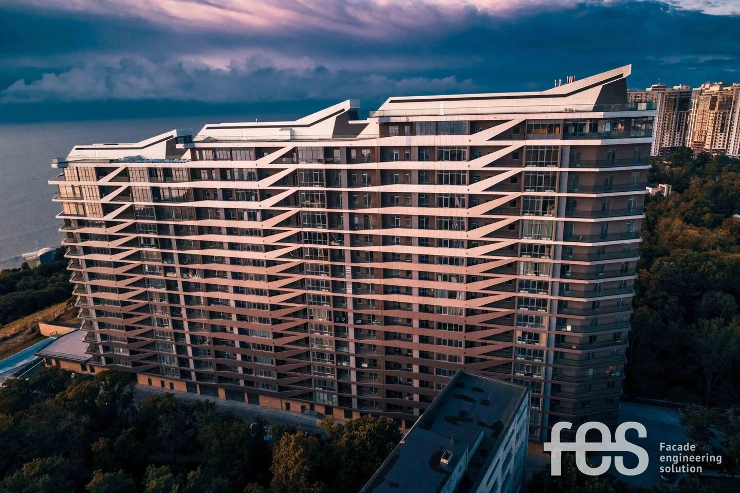 GreenWood: the long glazed elevation and balcony rhythm at dusk. FES project photograph.