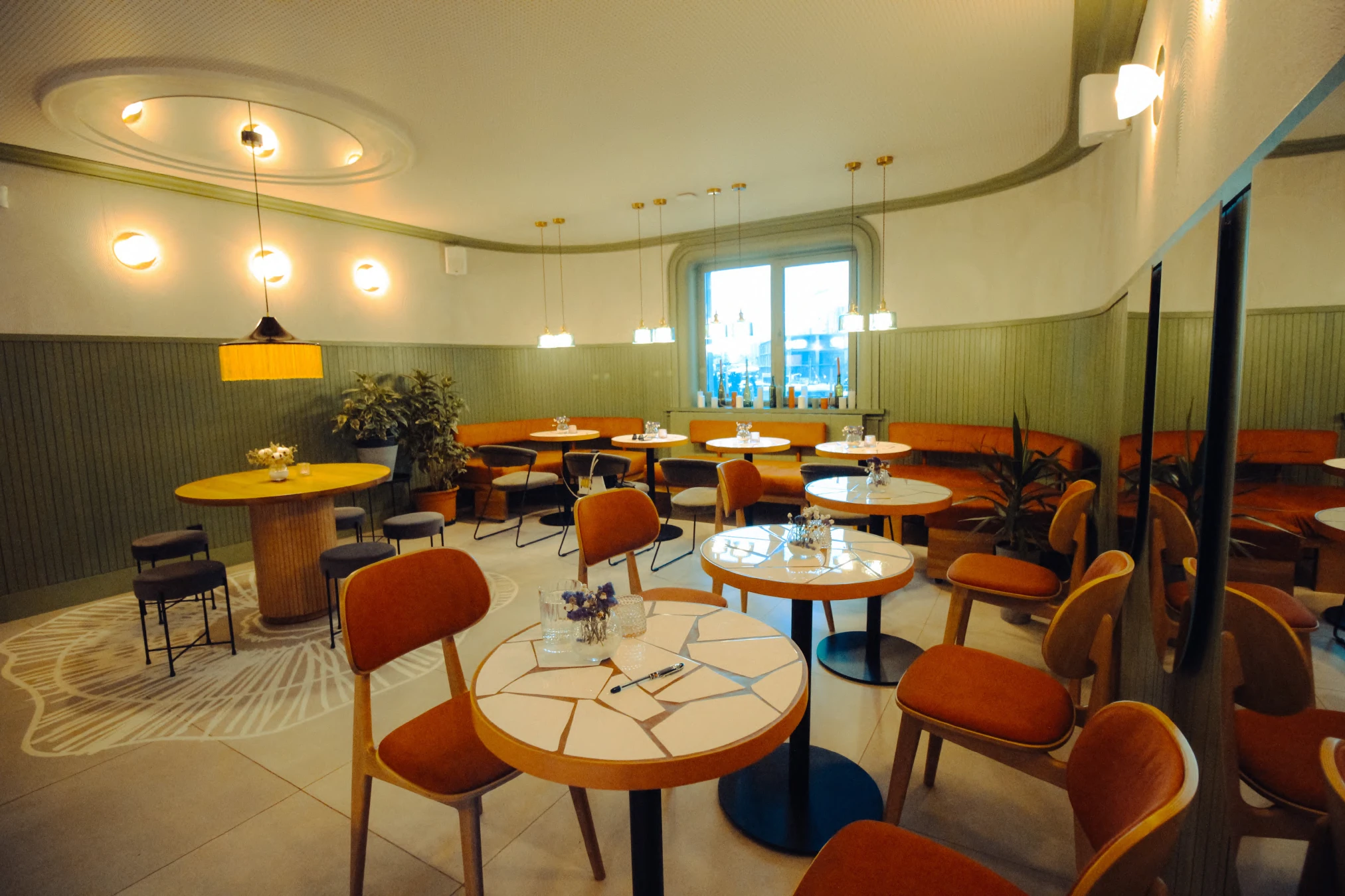 Tartateka: seating along the curved wall beneath warm pendant lights. Completed-interior photograph.