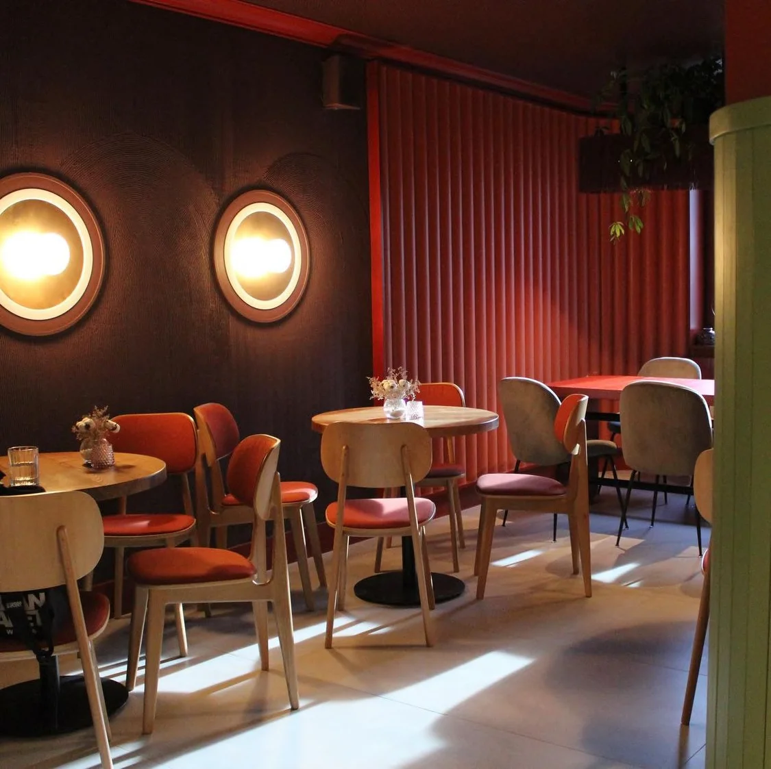 Tartateka: tables against the red wall and circular lights. Completed-interior photograph.