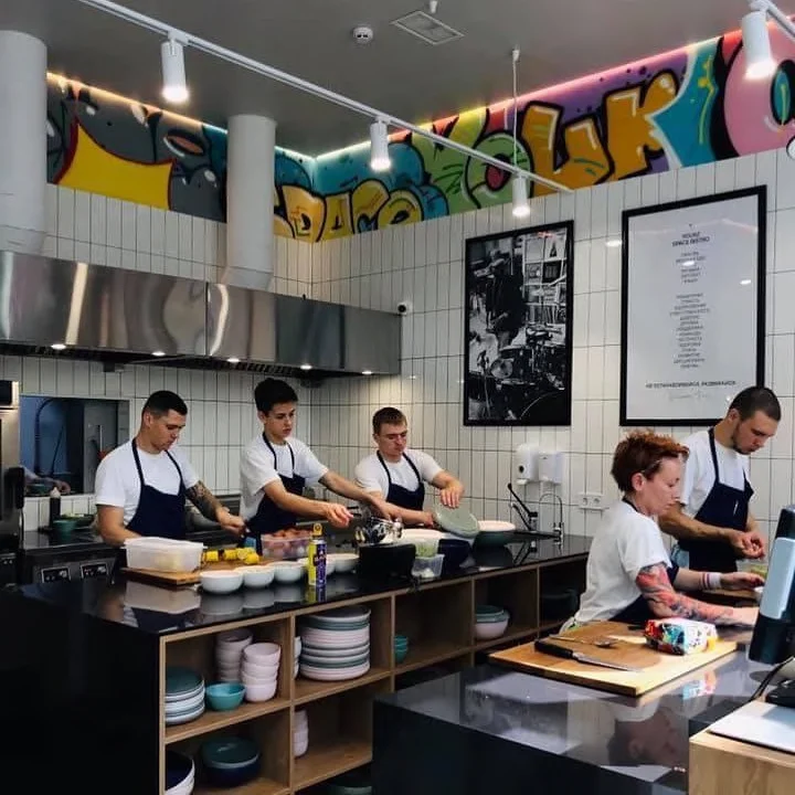 Yourz Bistro: the kitchen team working behind the open counter. Completed restaurant in operation; archive photograph.