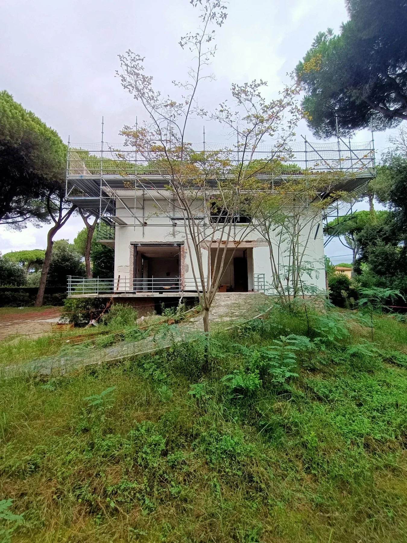 Garden-facing view of the villa beneath the roof scaffold. Site survey photograph, October 2024.