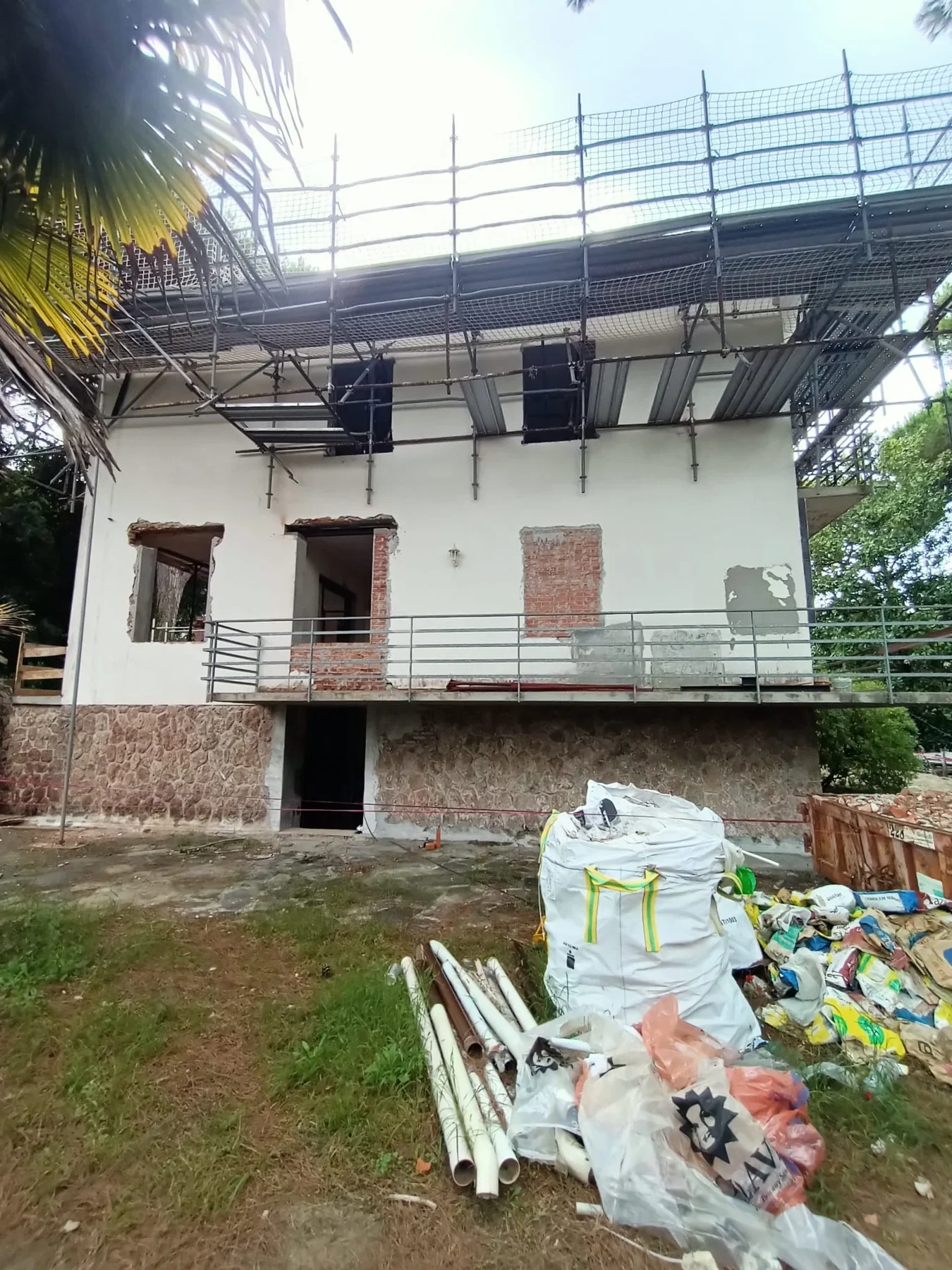 Side elevation of the villa during reconstruction, showing window openings, scaffold and site materials. October 2024.